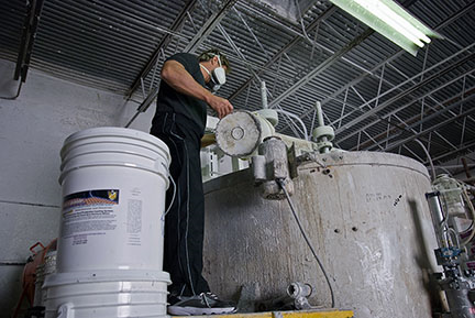 Technician operating liquid rubber blending tank at The Roof Store coating facility in Davie Florida